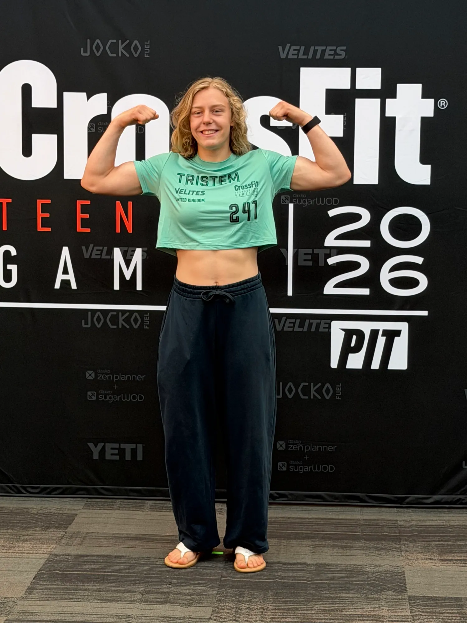 Lucy flexing in front of the CrossFit Teen Games 2026 backdrop at registration